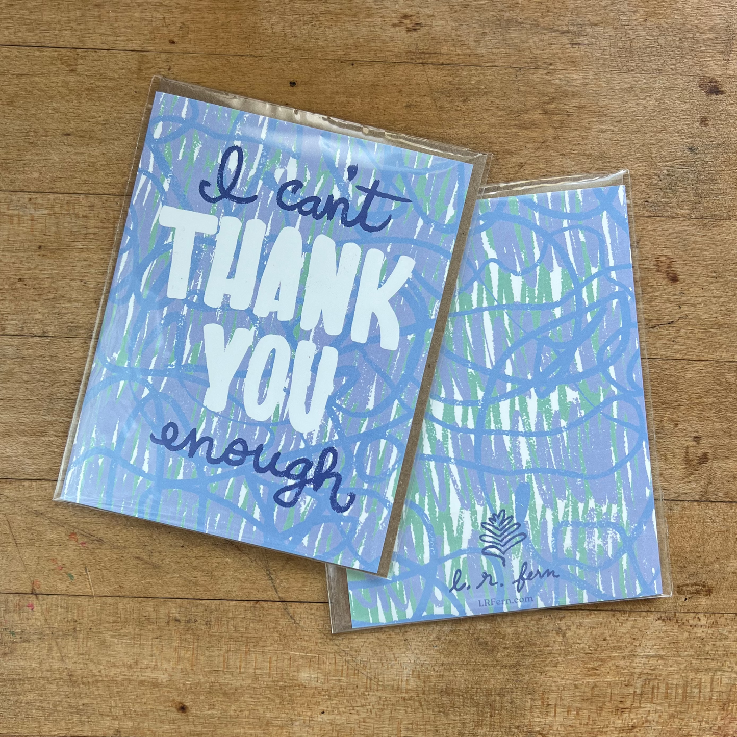 Two greeting cards on a wooden surface, one with 'I can't thank you enough' text.